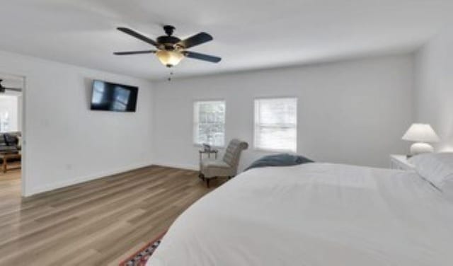 228 Stuart Dr, Karnack, TX 75661 - bedroom featuring multiple windows, baseboards, wood finished floors, and ceiling fan