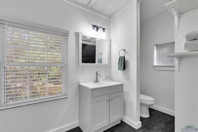 228 Stuart Dr, Karnack, TX 75661 - bathroom featuring toilet, baseboards, wood finished floors, vanity, and healthy amount of natural light