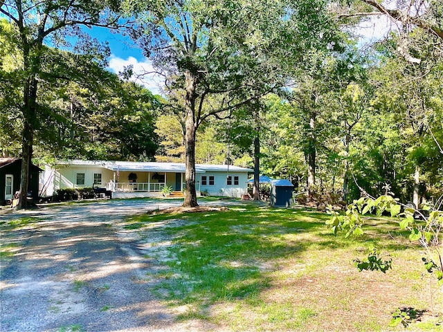 228 Stuart Dr, Karnack, TX 75661 - view of front of house featuring a porch, a storage shed, an outdoor structure, and a front lawn