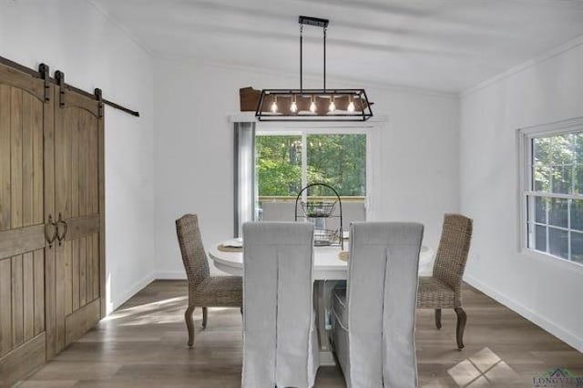 228 Stuart Dr, Karnack, TX 75661 - dining space with crown molding, a barn door, wood finished floors, and baseboards