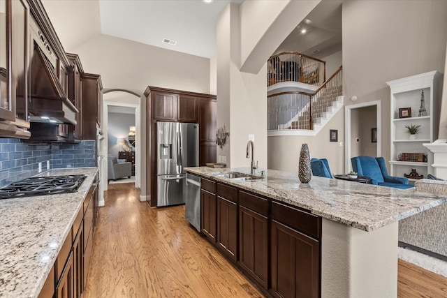 5581 Travis Dr, Frisco, TX 75034 - kitchen with a sink, stainless steel appliances, high vaulted ceiling, arched walkways, and light wood finished floors