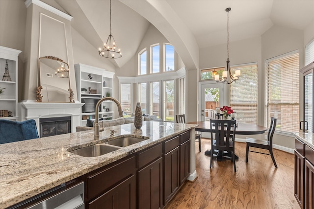 5581 Travis Dr, Frisco, TX 75034 - kitchen with a sink, a chandelier, dark brown cabinets, high vaulted ceiling, and light wood finished floors