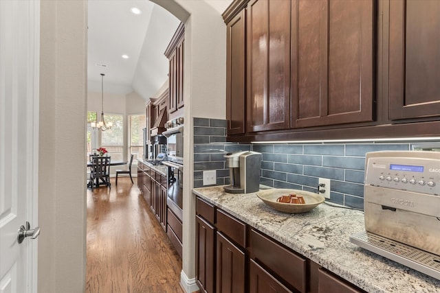 5581 Travis Dr, Frisco, TX 75034 - kitchen with backsplash, wood finished floors, lofted ceiling, dark brown cabinets, and light stone countertops