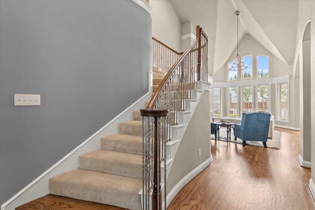 5581 Travis Dr, Frisco, TX 75034 - stairs featuring wood finished floors, high vaulted ceiling, baseboards, and a chandelier