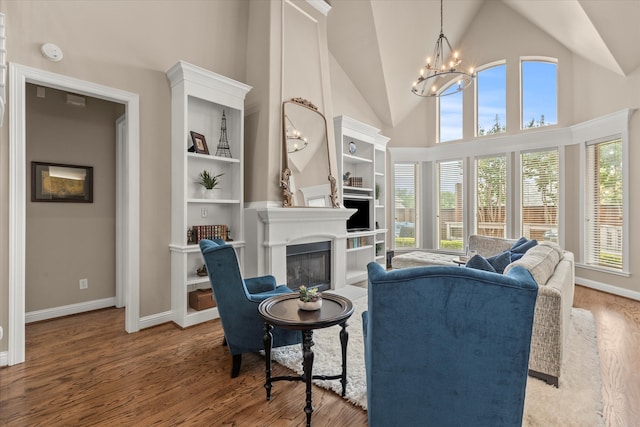 5581 Travis Dr, Frisco, TX 75034 - living room featuring a glass covered fireplace, a chandelier, wood finished floors, high vaulted ceiling, and baseboards