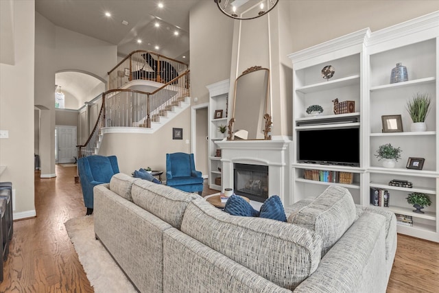 5581 Travis Dr, Frisco, TX 75034 - living area with stairs, a high ceiling, built in features, wood finished floors, and baseboards