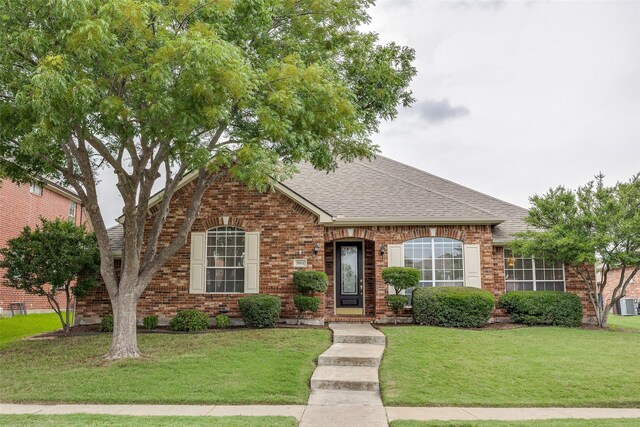 7002 Westover Dr, Rowlett, TX 75089 - view of front of house featuring roof with shingles, brick siding, a front yard, and central AC