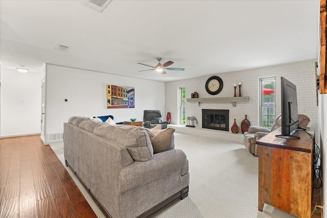 1247 Wedgewood Dr, Cleburne, TX 76033 - living area featuring a ceiling fan, plenty of natural light, wood finished floors, a fireplace, and brick wall