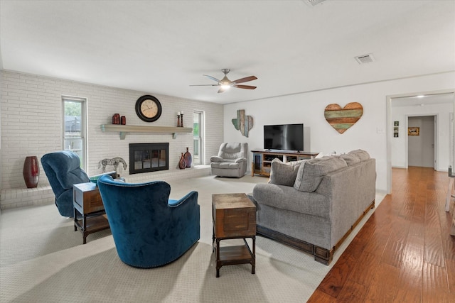 1247 Wedgewood Dr, Cleburne, TX 76033 - living area with wood finished floors, a ceiling fan, a brick fireplace, and brick wall