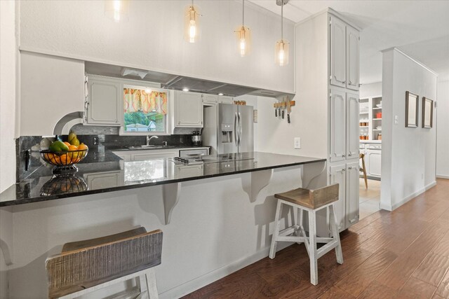 1247 Wedgewood Dr, Cleburne, TX 76033 - kitchen with stainless steel refrigerator with ice dispenser, a peninsula, wood finished floors, a sink, and backsplash
