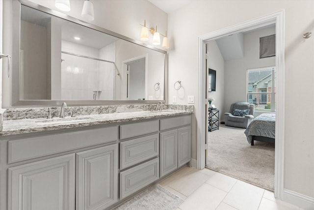 ensuite bathroom with double vanity, tiled shower, and tile patterned flooring