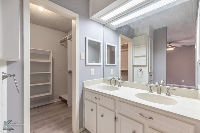 3242 Whitewing Way, Abilene, TX 79606 - full bath with a walk in closet, double vanity, a textured ceiling, wood finished floors, and a ceiling fan