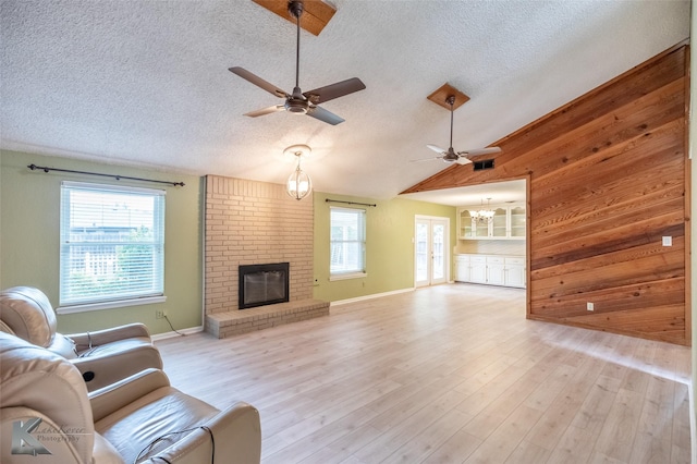 3242 Whitewing Way, Abilene, TX 79606 - living area featuring a textured ceiling, a ceiling fan, plenty of natural light, a fireplace, and lofted ceiling