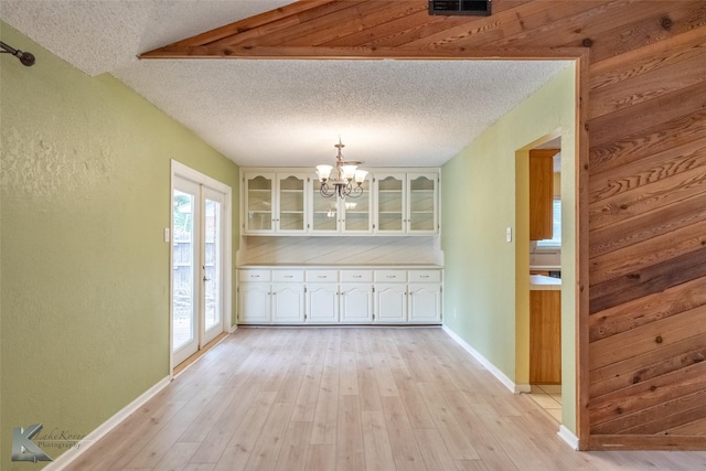 3242 Whitewing Way, Abilene, TX 79606 - unfurnished dining area with a textured ceiling, a textured wall, a chandelier, light wood finished floors, and baseboards