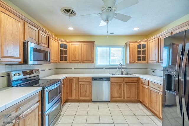 3242 Whitewing Way, Abilene, TX 79606 - kitchen with appliances with stainless steel finishes, a sink, backsplash, and tile countertops