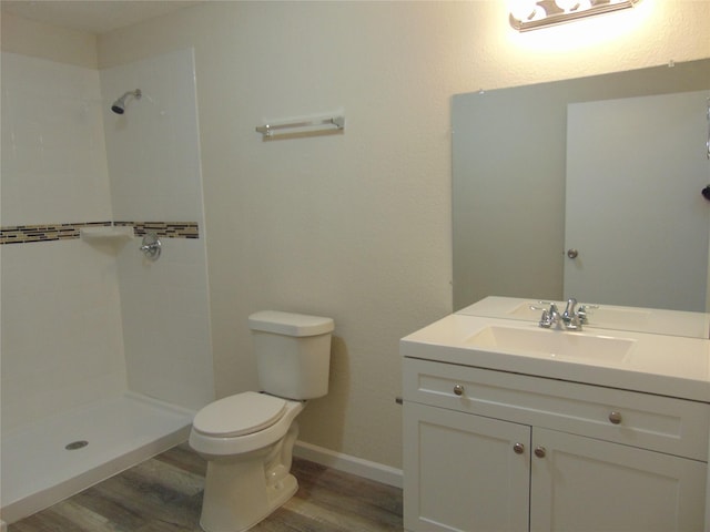 7928 Hull Ave, Dallas, TX 75216 - full bathroom featuring wood finished floors, toilet, a tile shower, vanity, and baseboards
