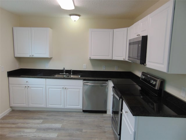 7928 Hull Ave, Dallas, TX 75216 - kitchen with appliances with stainless steel finishes, a sink, white cabinets, light wood-style floors, and a textured ceiling