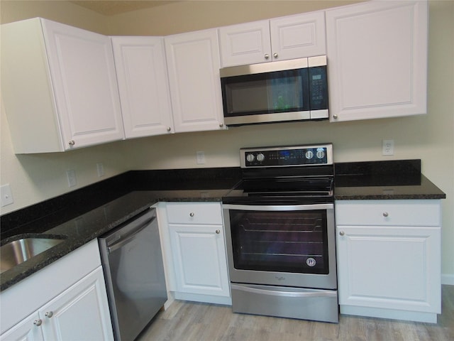 7928 Hull Ave, Dallas, TX 75216 - kitchen with appliances with stainless steel finishes, white cabinets, light wood-style floors, dark stone counters, and a sink