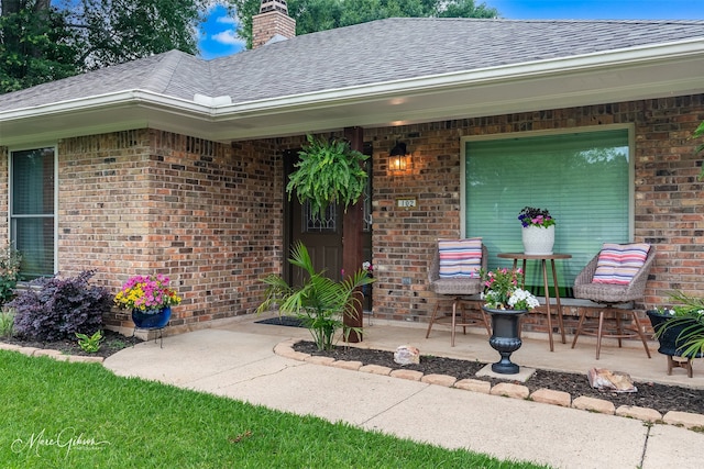 102 Pinehurst Pl, Benton, LA 71006 - entrance to property featuring a shingled roof, brick siding, a chimney, and a patio area