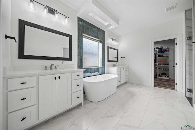 316 Heritage Way, Bullard, TX 75757 - bathroom featuring marble look tile flooring, two vanities, a soaking tub, and a walk in closet