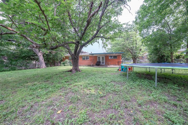 8820 Easley St, White Settlement, TX 76108 - view of grassy yard featuring a trampoline and french doors