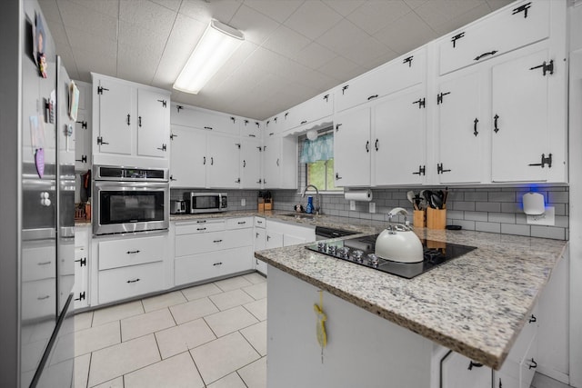 4900 Ira St, Haltom City, TX 76117 - kitchen featuring appliances with stainless steel finishes, backsplash, a sink, and white cabinetry