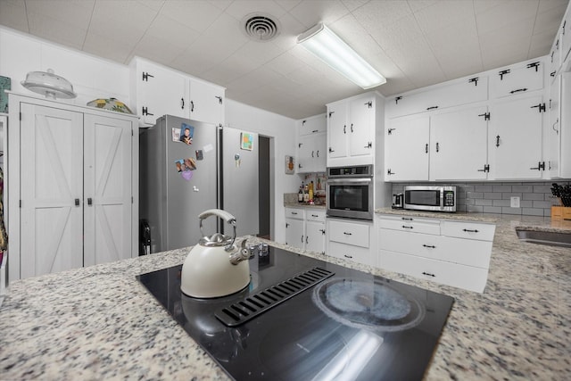 4900 Ira St, Haltom City, TX 76117 - kitchen with stainless steel appliances, white cabinetry, tasteful backsplash, and light stone counters