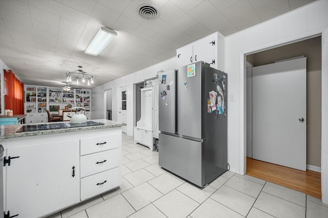 4900 Ira St, Haltom City, TX 76117 - kitchen featuring freestanding refrigerator, light tile patterned flooring, white cabinetry, black electric stovetop, and light stone counters