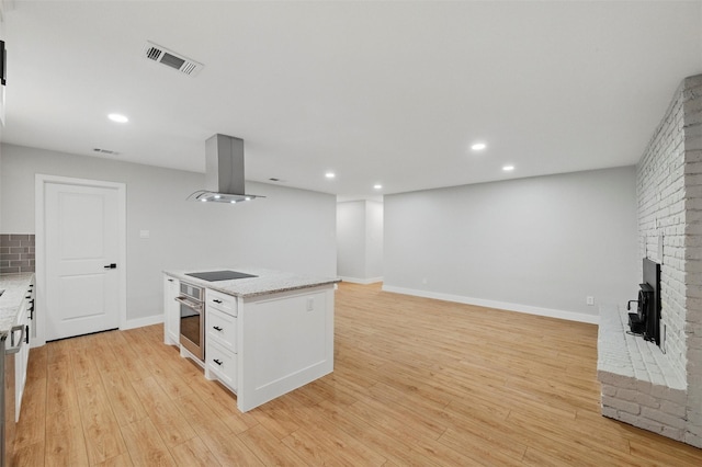742 Chalk Hill Ln, Desoto, TX 75115 - kitchen with island range hood, oven, white cabinetry, light wood-style flooring, and light stone countertops