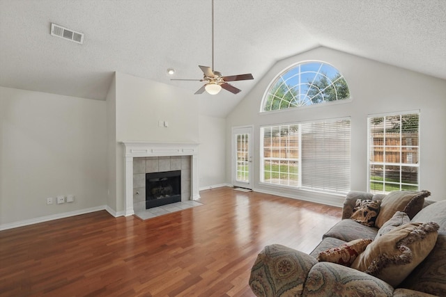 8100 Hosta Way, Fort Worth, TX 76123 - living area with a ceiling fan, a tile fireplace, wood finished floors, a textured ceiling, and high vaulted ceiling