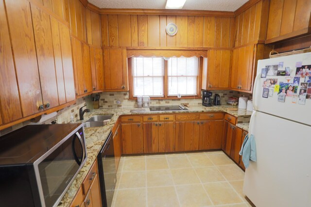 1000 S Harrison St, Mcgregor, TX 76657 - kitchen with black appliances, a sink, brown cabinets, decorative backsplash, and wooden walls