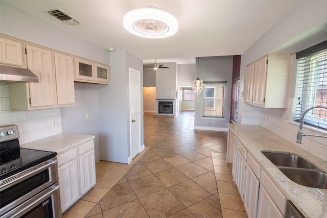 417 Red Coat Ln, Arlington, TX 76002 - kitchen featuring range with two ovens, under cabinet range hood, a sink, and decorative backsplash