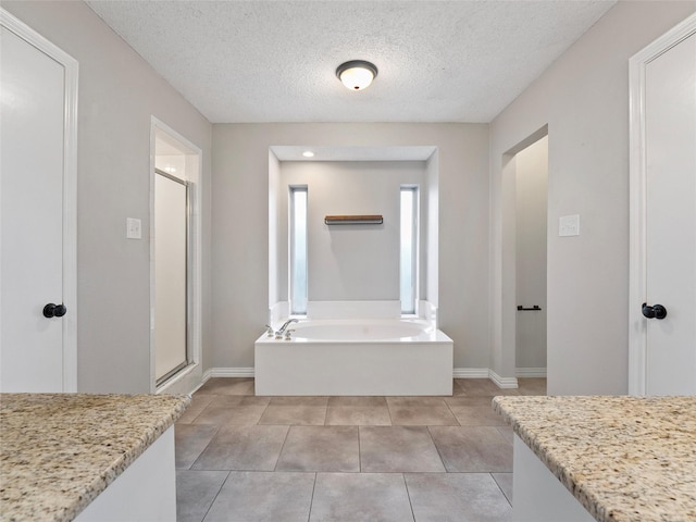 4509 Trowbridge Dr, Arlington, TX 76013 - full bathroom with a shower stall, a bath, baseboards, a textured ceiling, and tile patterned flooring