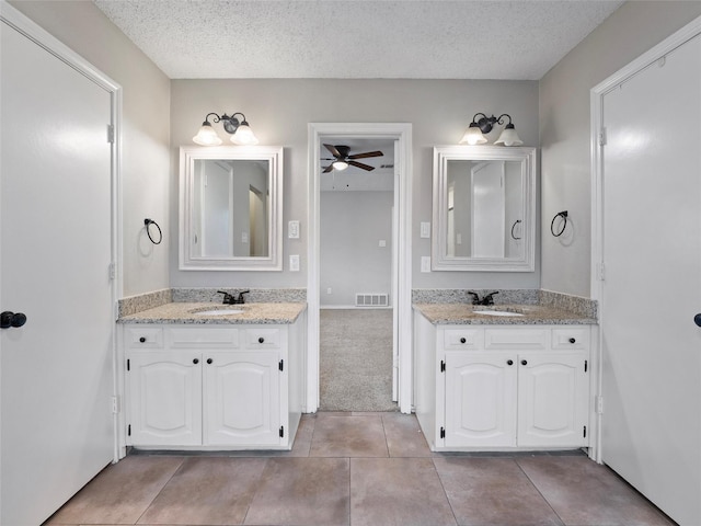 4509 Trowbridge Dr, Arlington, TX 76013 - bathroom with a textured ceiling, a ceiling fan, two vanities, and tile patterned flooring