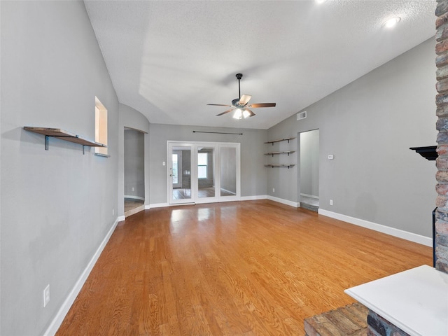 4509 Trowbridge Dr, Arlington, TX 76013 - unfurnished living room with lofted ceiling, a ceiling fan, light wood-style flooring, baseboards, and a textured ceiling