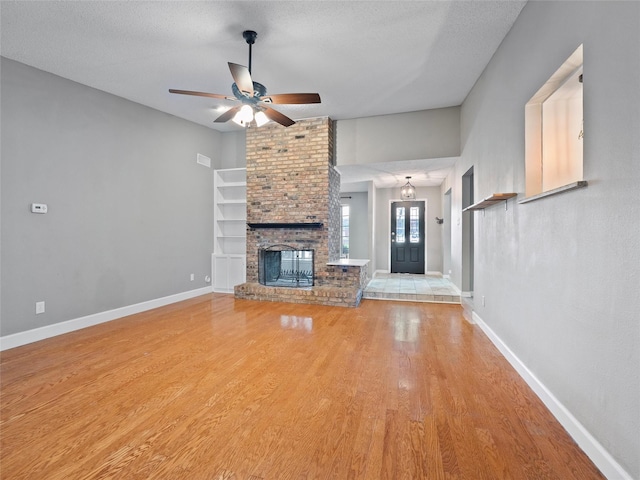 4509 Trowbridge Dr, Arlington, TX 76013 - unfurnished living room featuring a ceiling fan, light wood-style flooring, a fireplace, a textured ceiling, and baseboards