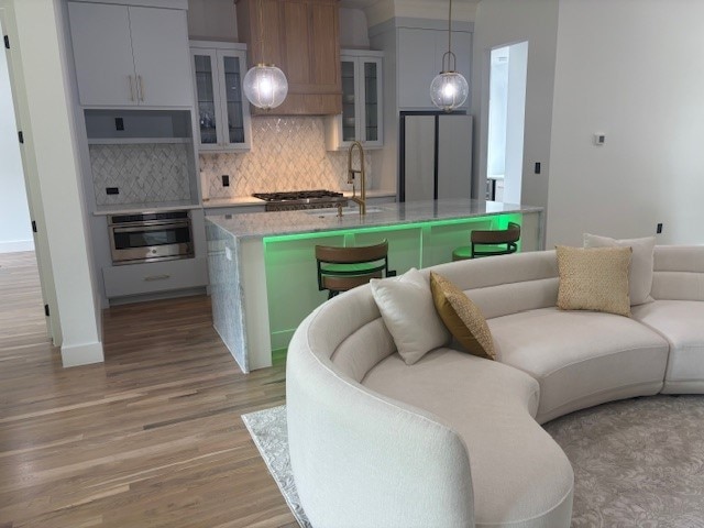 5073 Loper Cir, Streetman, TX 75859 - kitchen featuring stainless steel appliances, a sink, open floor plan, decorative backsplash, and light wood finished floors
