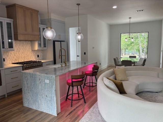 5073 Loper Cir, Streetman, TX 75859 - kitchen featuring dark wood-style floors, decorative backsplash, stainless steel gas cooktop, a breakfast bar area, and a center island with sink