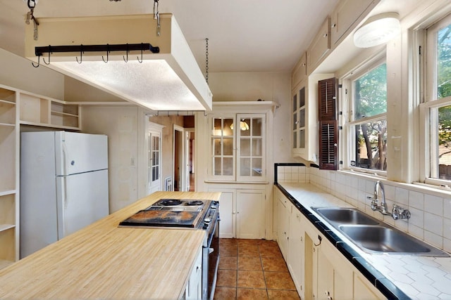 1022 N Edgefield Ave, Dallas, TX 75208 - kitchen with freestanding refrigerator, stainless steel electric range, a sink, backsplash, and glass insert cabinets