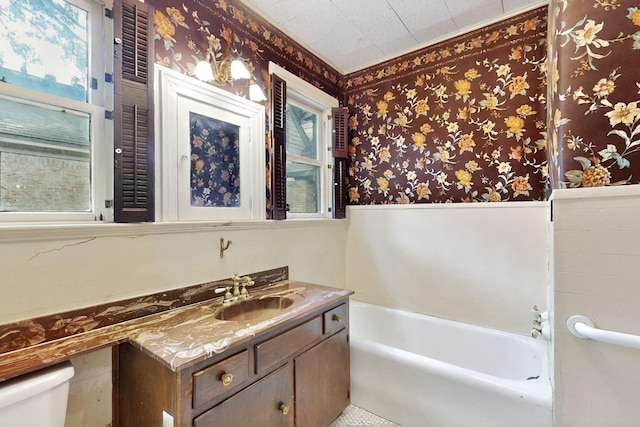 1022 N Edgefield Ave, Dallas, TX 75208 - full bath featuring wallpapered walls, a garden tub, vanity, toilet, and a wainscoted wall