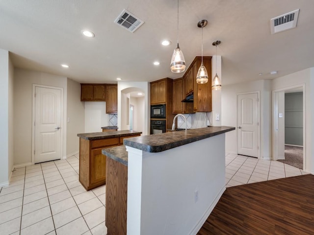 712 Hardwood Dr, Mckinney, TX 75069 - kitchen with dark countertops, black appliances, light tile patterned flooring, arched walkways, and baseboards