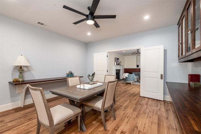 812 Baker St, Mckinney, TX 75069 - dining area with a fireplace, a ceiling fan, light wood-style floors, and recessed lighting
