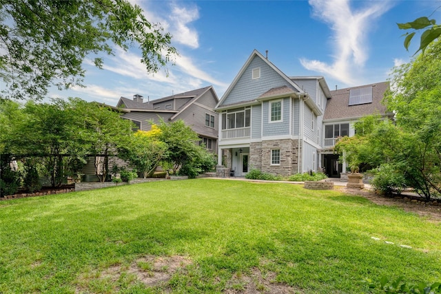 812 Baker St, Mckinney, TX 75069 - rear view of house with stone siding, solar panels, and a lawn