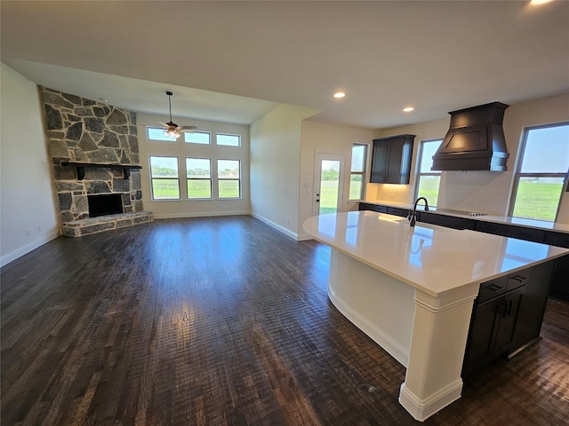 320 Magnolia Ct, Trenton, TX 75490 - kitchen featuring premium range hood, a center island with sink, dark wood-style flooring, a ceiling fan, and baseboards