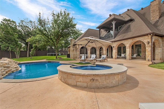 view of pool with a patio area, an in-ground hot tub, fence, and a trampoline