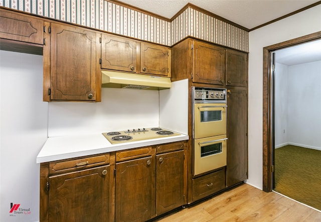 5023 Dedman Dr, Shreveport, LA 71107 - kitchen featuring multiple ovens, white electric stovetop, under cabinet range hood, crown molding, and light countertops