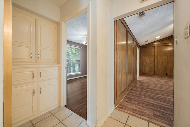 1111 Lupine Dr, Garland, TX 75043 - hall featuring a textured ceiling, light tile patterned floors, baseboards, and lofted ceiling