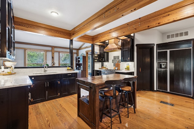 831 Old Justin Rd, Argyle, TX 76226 - kitchen featuring black fridge with ice dispenser, premium range hood, dark cabinets, light wood-style flooring, and beamed ceiling