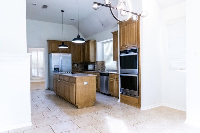 2104 Hunter Place Ln, Arlington, TX 76006 - kitchen featuring stainless steel appliances, lofted ceiling, tasteful backsplash, a kitchen island, and hanging light fixtures