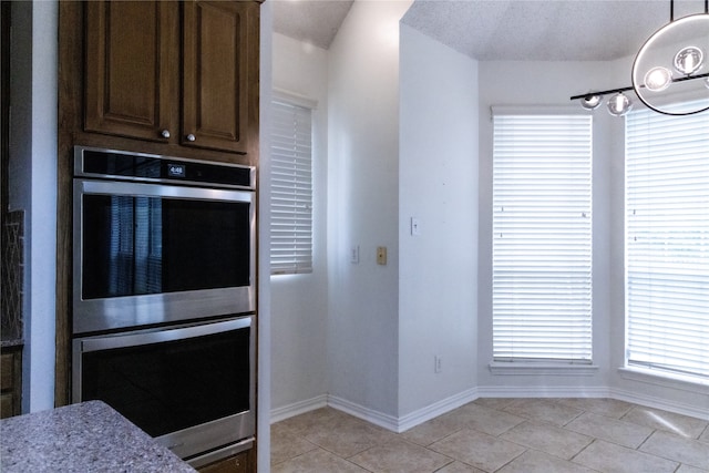 2104 Hunter Place Ln, Arlington, TX 76006 - kitchen featuring double oven, light tile patterned flooring, baseboards, hanging light fixtures, and light stone counters